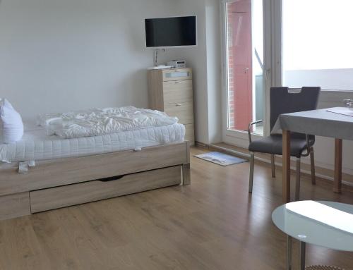 Un dormitorio con una cama, un escritorio y una mesa. en Tief 10 Deck 7, en Wangerland