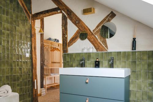ein Bad mit einem Waschbecken und einem Spiegel in der Unterkunft Les Callots - Maison d'hôtes in Champignelles