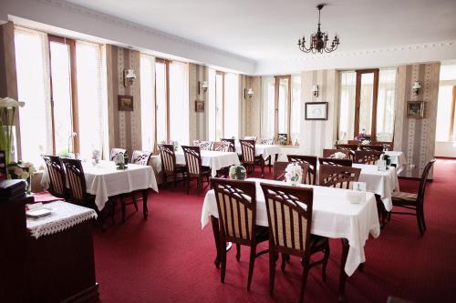 un comedor con mesas y sillas blancas y ventanas en Hotel Horda en Słubice