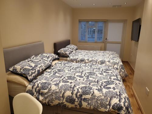 伊爾福德的住宿－London Luxury Apartments 3 Bedroom Sleeps 8 with 3 Bathrooms 5 mins Walk to tube station free parking，一间卧室设有两张床、一个窗口和椅子