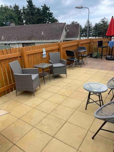 a patio with chairs and tables and a fence at Harmony House enclosed property near beach and lake in Tramore