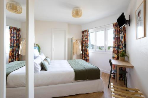 a bedroom with a bed and a desk and window at Hôtel Suzane in Angers