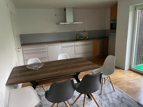 a kitchen with a wooden table and white chairs at Bungalow in ruhiger Siedlung mit Terrasse und Stellplatz in Landshut