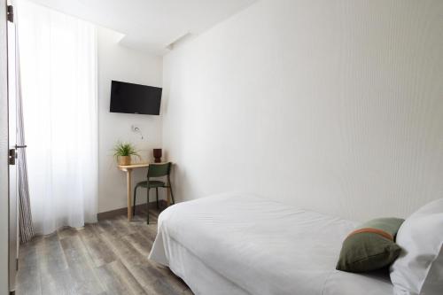 a white bedroom with a bed and a table at Hôtel Suzane in Angers