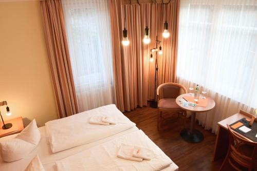 a hotel room with a bed and a chair and a table at Pension Sanddorn mit Café Carlssons in Binz