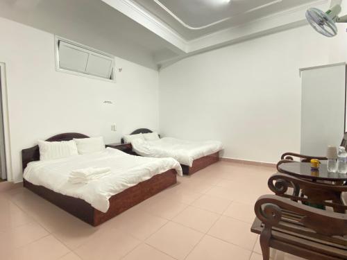 two beds in a room with white walls at VALENTINEdalat Hotel in Da Lat