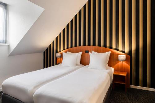two beds in a hotel room with two pillows at Aris Grand Place Hotel in Brussels