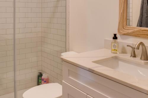 a white bathroom with a sink and a toilet at Cozy Tennessee Cabin with Deck, Grill and Fire Pit! in Tullahoma