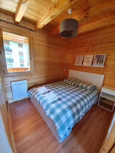 une chambre avec un lit dans une cabane en bois dans l'établissement Charmant Appartement Bozel Centre, à Bozel