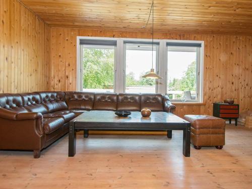 ein Wohnzimmer mit einem braunen Ledersofa und einem Tisch in der Unterkunft 6 person holiday home in Glesborg in Glesborg