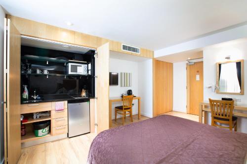 a bedroom with a bed and a kitchen and a table at The Cleveland in London