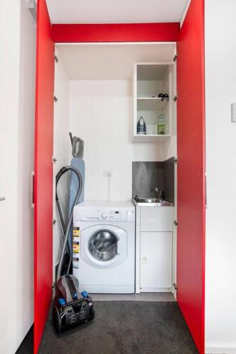 a small kitchen with a washing machine in a red door at The Zen Apartments with Urban Soul in Adelaide