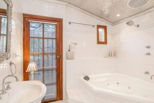 Baño blanco con bañera y lavamanos en Firebird Cottage A Hallmark to Adelaides History, en Bowden