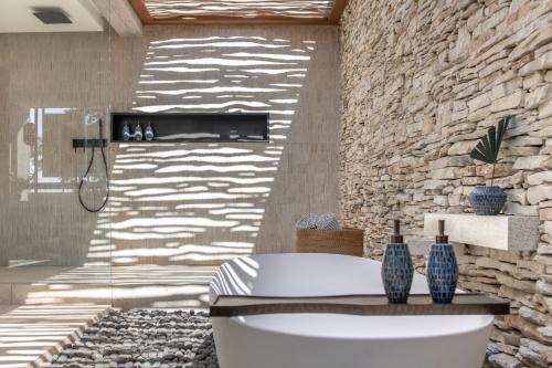 a bathroom with a toilet and a stone wall at Cap Karoso Sumba - a member of Design Hotels 