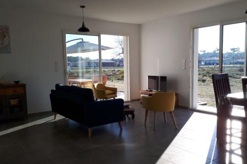ein Wohnzimmer mit Stühlen, einem TV und Fenstern in der Unterkunft Montalivet à 1km,Villa(jardin)à 1km plages wifi in Vensac