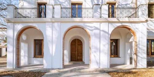 a white house with arches and a wooden door at Can Passarells in San Vicente de Torelló