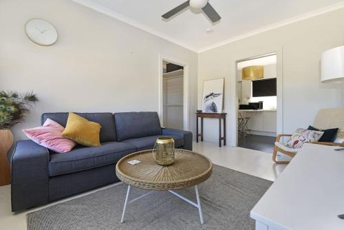 a living room with a blue couch and a table at Beachy Keen in Gorgeous Henley Beach in Henley Beach