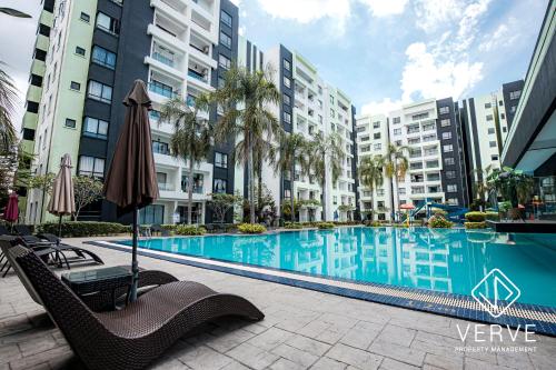 ein Pool mit Stühlen und einem Sonnenschirm sowie einige Gebäude in der Unterkunft Ipoh Manhattan Premium Suites by Verve in Ipoh