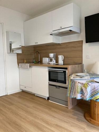 a small kitchen with white cabinets and a microwave at Charmant Studio à Boulogne Nord proche porte d'Auteuil in Boulogne-Billancourt