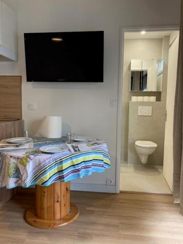 a room with a table and a television on the wall at Charmant Studio à Boulogne Nord proche porte d'Auteuil in Boulogne-Billancourt