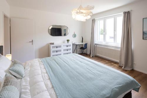 a white bedroom with a bed and a desk at STAYY Bijou Balgrist nahe Spital - gratis Parkplatz in Zürich