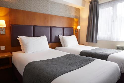 a hotel room with two beds and a window at De Trafford Arms by Chef & Brewer Collection in Alderley Edge