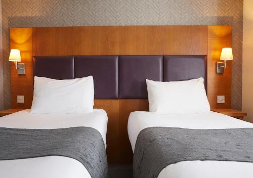a hotel room with two beds and a headboard at De Trafford Arms by Chef & Brewer Collection in Alderley Edge