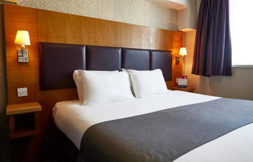 a hotel room with a large bed with white pillows at De Trafford Arms by Chef & Brewer Collection in Alderley Edge