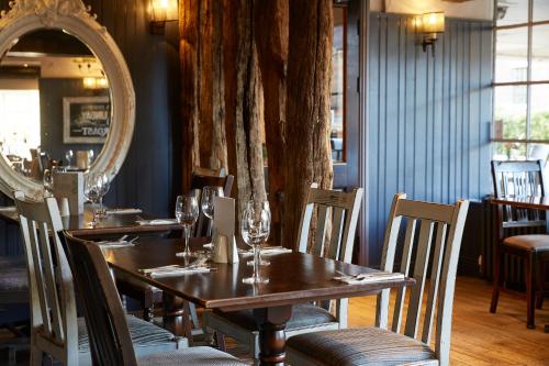 a dining room with a table with chairs and a mirror at De Trafford Arms by Chef & Brewer Collection in Alderley Edge