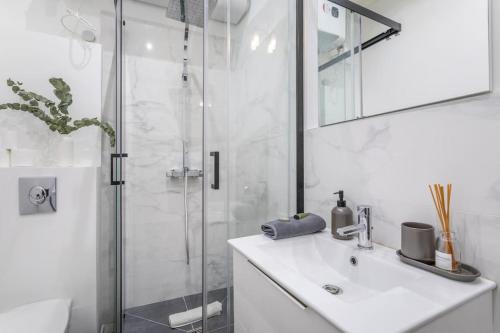 une salle de bain blanche avec un lavabo et une douche dans l'établissement Cosy appartement au coeur du cours Julien, à Marseille