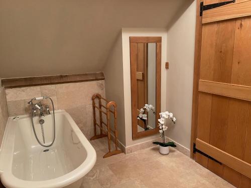 uma casa de banho com uma banheira e um lavatório em Yew Tree Cottage em Shepton Mallet