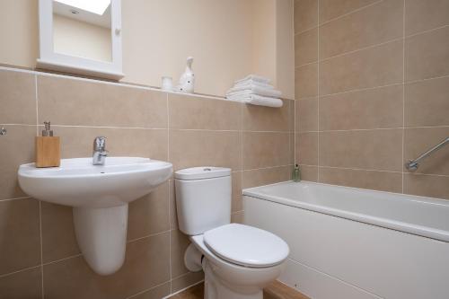 a bathroom with a toilet and a sink and a bath tub at Cosy coach house in historical Tetbury in Tetbury