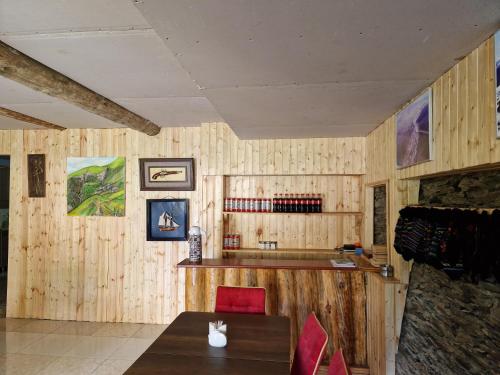 comedor con paredes de madera, mesa y sillas en Guesthouse Mevele en Omalo