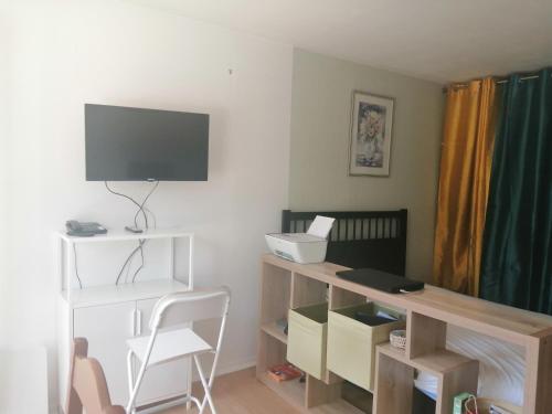 a room with a desk with a television and a chair at KIEVAILLE in Plaisir