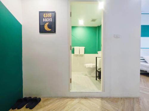 a bathroom with a mirror and a toilet and green walls at Ostay Asoke Bangkok in Makkasan