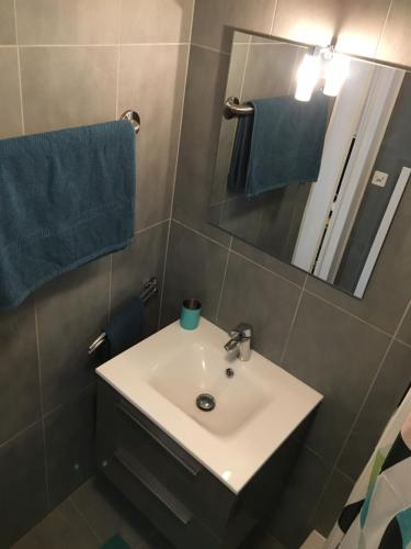 een badkamer met een wastafel, een spiegel en blauwe handdoeken bij Loft with rooftop, stunning view of the lake! in Montreux