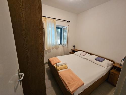 um quarto com uma cama com lençóis brancos e uma janela em Amazing View Apartment in the heart of Postira em Postira