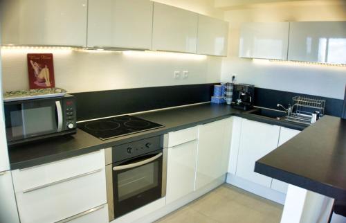 une cuisine avec des armoires blanches et un comptoir noir dans l'établissement Ref MIDI - Palmes d'Or Properties, à Cannes