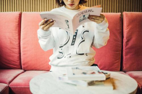 a woman reading a book in front of a table at Hotel She, Kyoto in Kyoto