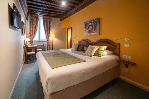 a bedroom with a large bed with yellow walls at Hôtel Wilson - Teritoria in Dijon