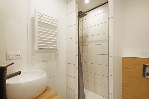 biała łazienka z umywalką i prysznicem w obiekcie L'Epicéa - Appartement vue montagne w mieście La Bresse