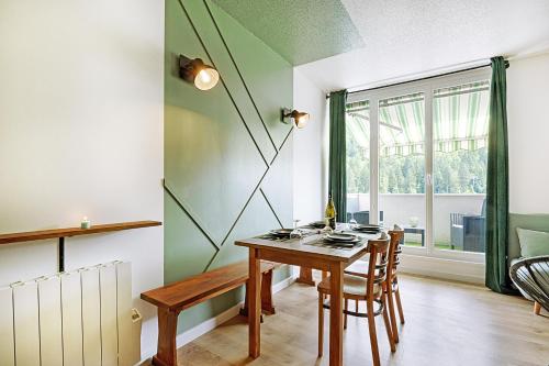 une salle à manger avec une table en bois et une fenêtre dans l'établissement L'Epicéa - Appartement vue montagne, à La Bresse