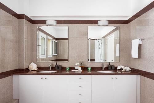 a bathroom with two sinks and two mirrors at Eretria Luxurious Seafront Villa in Chalkida
