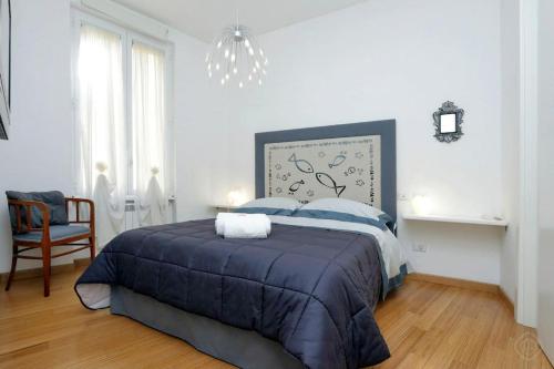 a white bedroom with a blue bed and a chandelier at Karol Apartment Rome in Rome