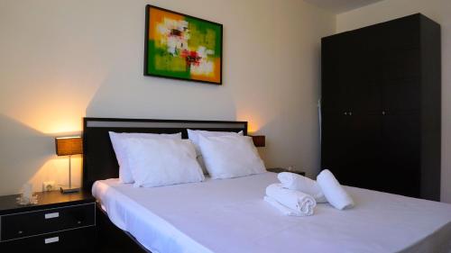 a bedroom with a bed with two towels on it at Бяла Виста Бийч Апартментс A - Byala Vista Beach Apartments A in Byala