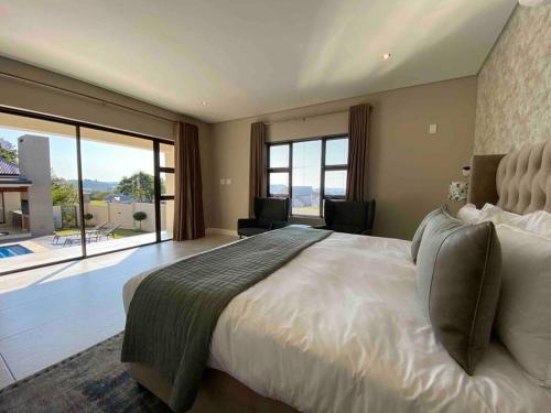 a large bedroom with a large bed and large windows at Khaya Elihle Guest House in Hazyview