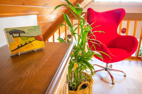 a red chair sitting next to a painting and a plant at Annie's Place - a downtown, mezzanine apartment in Albany