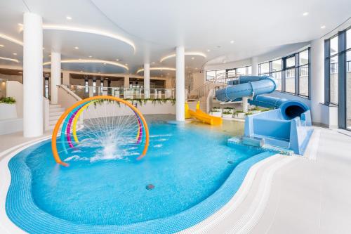een groot zwembad met een glijbaan in een gebouw bij FARO Apartamenty Polanki Aqua Morskie Klimaty 4 baseny free parking in Kołobrzeg