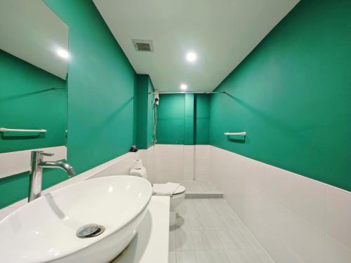 a bathroom with a white sink and green walls at Ostay Asoke Bangkok in Makkasan