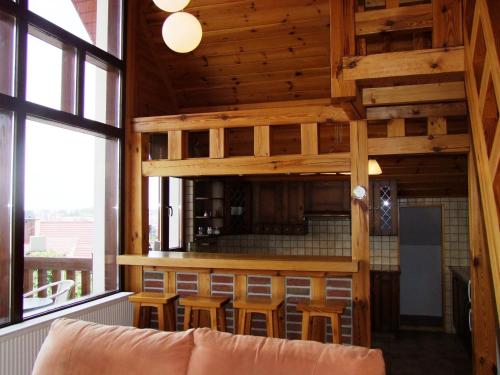 a living room with wooden ceilings and a bar with stools at Panorama Mikołajki Mazurski-zakątek in Mikołajki